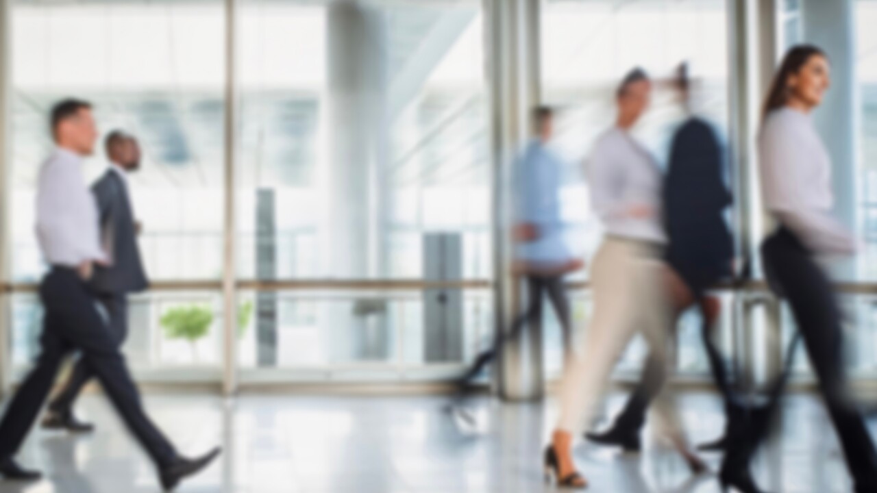 People walking along a corridor with floor to ceiling windows