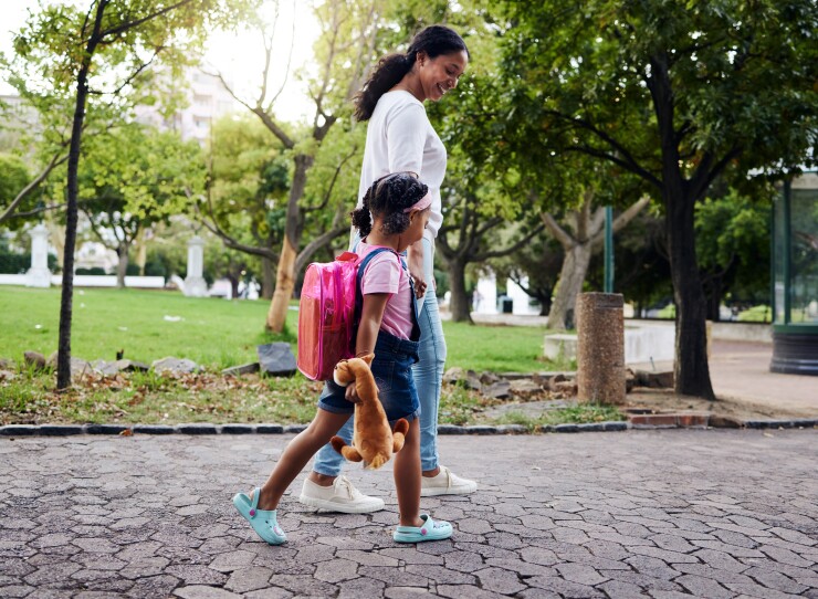 Mother and daughter walking on sidewalk