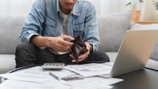 Man looking at empty wallet, money help