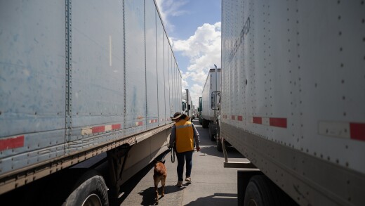 A picture of a security guard and K-9 unit checking trucks entering the U.S. from Mexico.