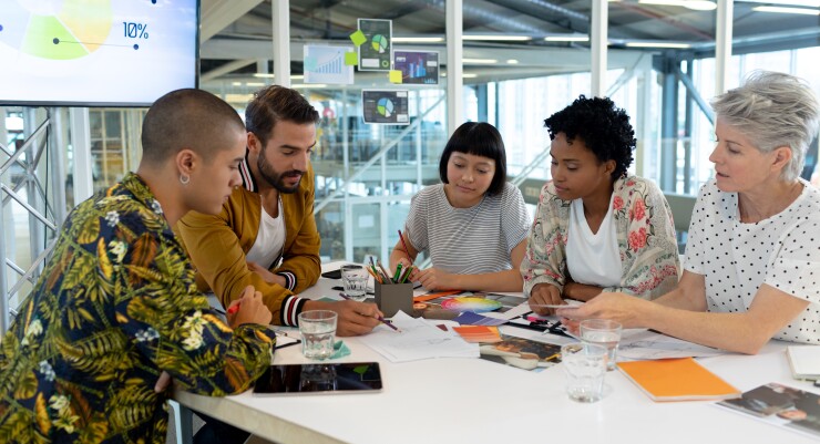Group of employees sitting around table working in office