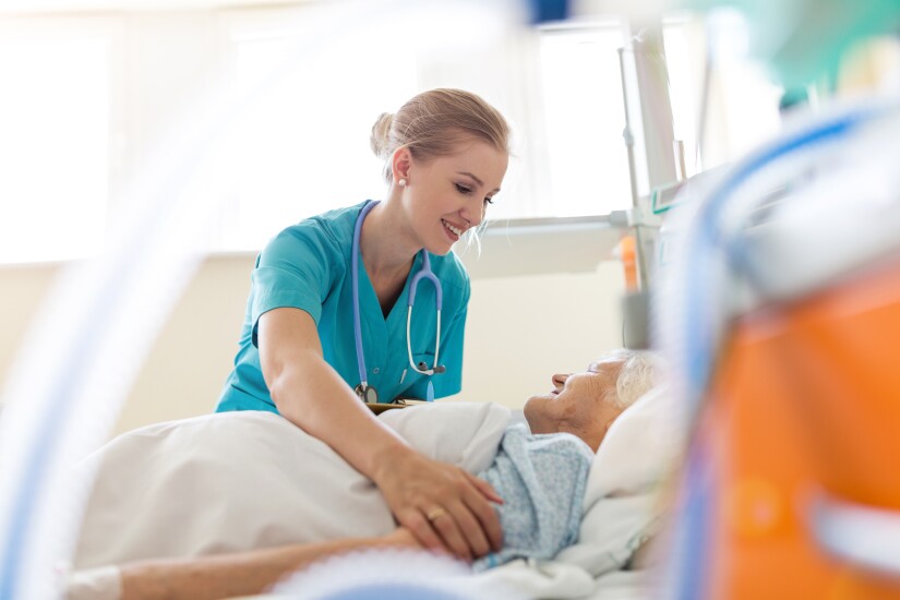 Nurse helping patient in hospital bed