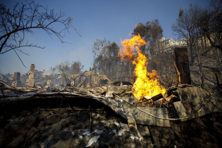Flames burn from a destroyed home's natural gas line during the Skirball Fire in the Bel Air neighborhood of Los Angeles, California, U.S., on Wednesday, December 6, 2017.