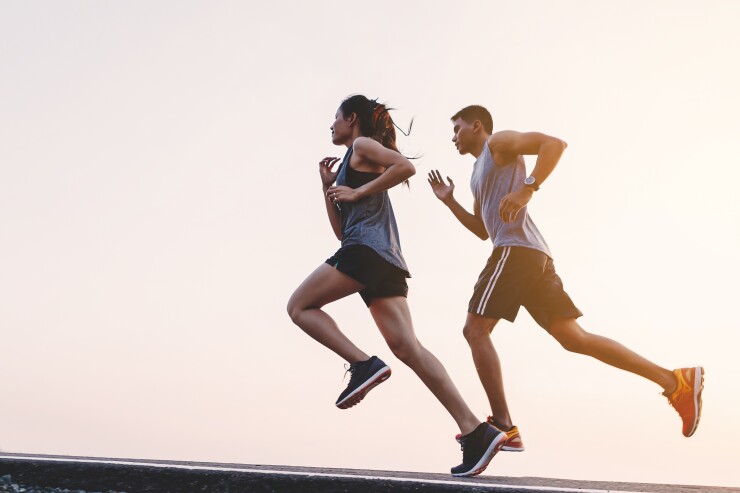 A woman and man are running side-by-side at sunrise.