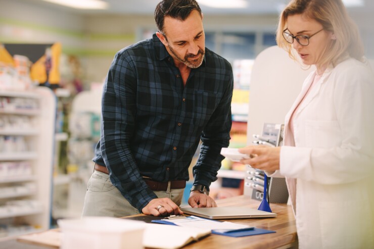 Man looking at medication with pharmacist at pharmacy