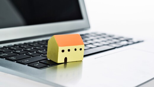 Wooden house model on laptop keyboard