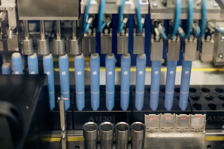 Weight loss drug shots in blues capsules lined up in a factory