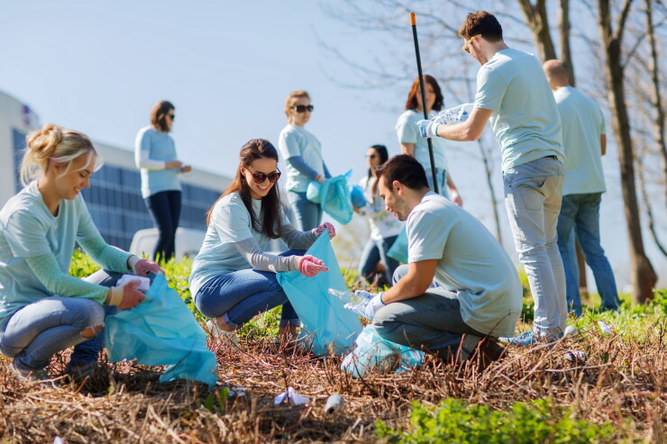 Volunteers with garbage bags cleaning park area.