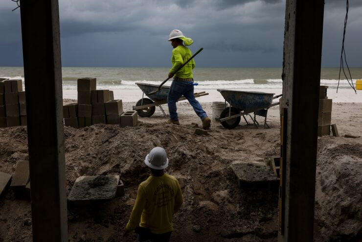Workers haul sand near home under renovation following damage from Hurricane Ian in Fort Myers Beach, Florida
