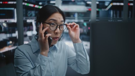 Female Trader Speaks on Smartphone While Executing Stock Market Operations on Computer