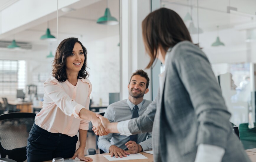 Colleagues shake hands at a conference table.
