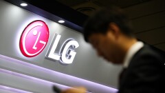 A visitor checks a smartphone in front of an LG Electronics Inc. logo displayed at the World IT Show 2018 in Seoul, South Korea/