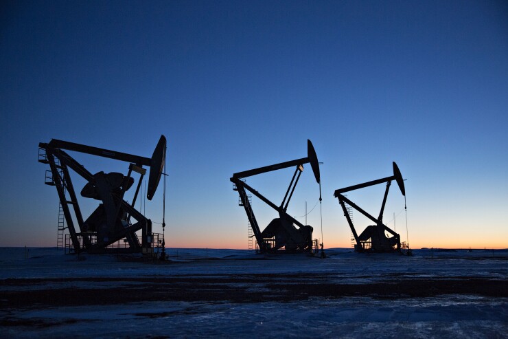 The silhouettes of pumpjacks are seen above oil wells in the Bakken Formation in North Dakota.
