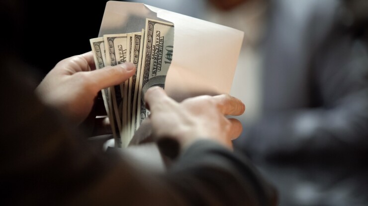 Man receiving an envelope full of cash and opening it to look at it.
