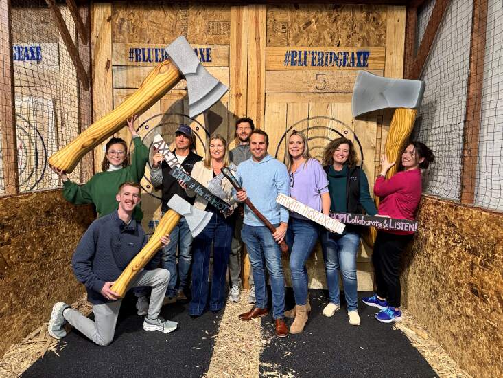 KlariVis employees holding up various axe props at a throwing range.