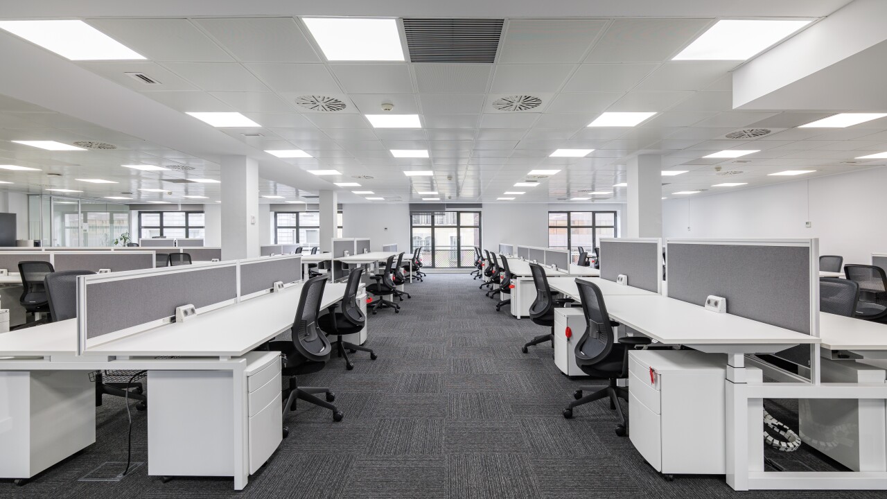 Modern corporate open office in minimalist modern design in whites and greys, empty office workstations.