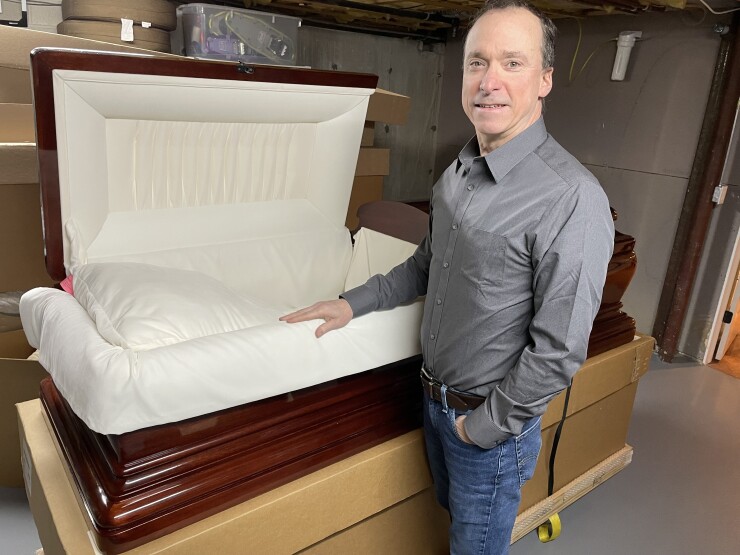 A man standing next to a casket.