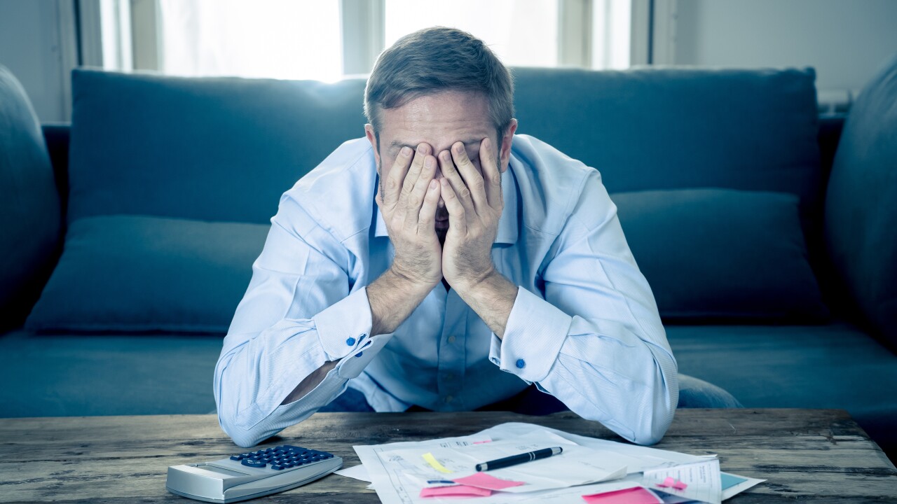 Upset man in stress paying bills counting finance with calculato