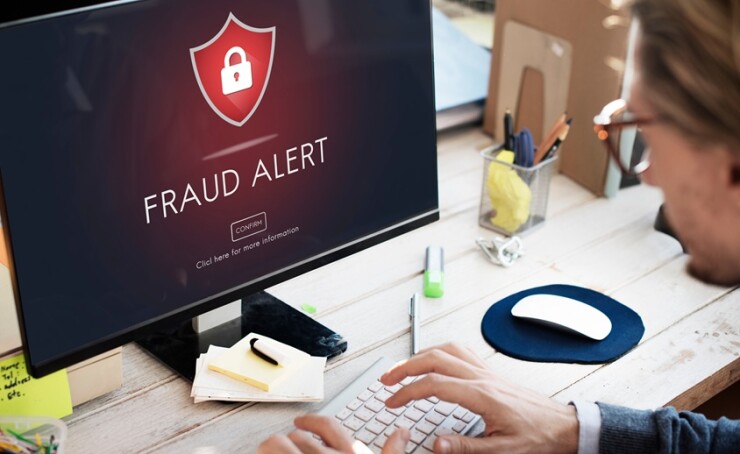 Fraud alert pops up on the computer screen in front of a man