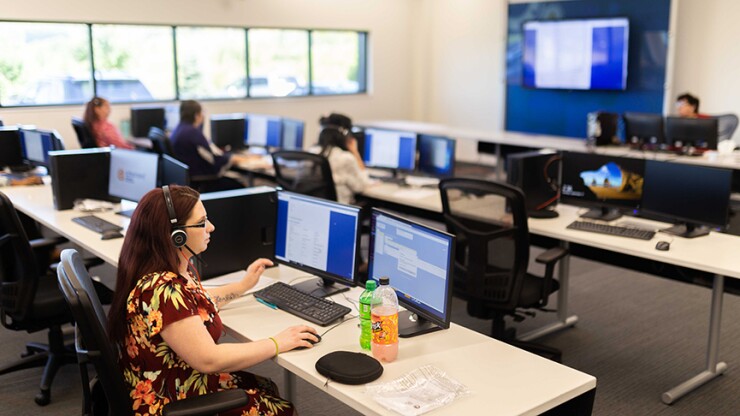Multiple people working on computers in a tech environment.