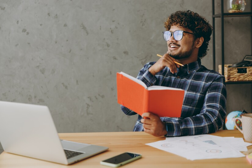 Man reading book at office desk