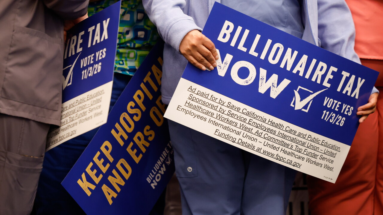Supporters hold signs advocating for the Billionaire Tax Now coalition in Los Angeles in April