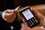 A customer holds a contactless debit card issued by HSBC near a Worldpay payment terminal.