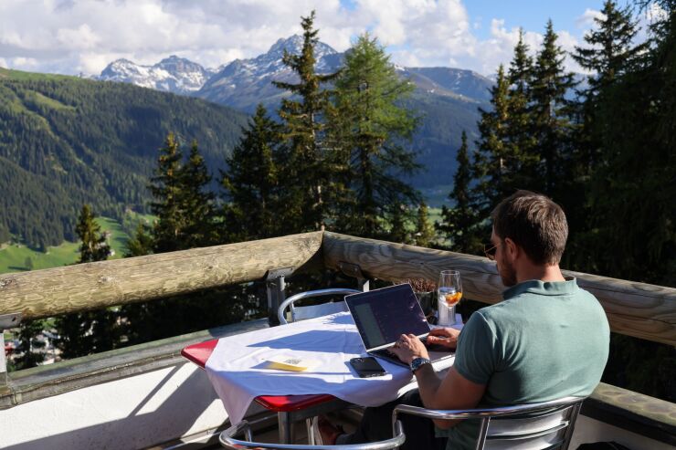 A customer works from a laptop on the terrace of a mountain restaurant on the Schatzalp on the closing day of the World Economic Forum (WEF) in Davos, Switzerland, on Thursday, May 26, 2022. The annual Davos gathering of political leaders, top executives and celebrities runs from May 22 to 26. Photographer: Hollie Adams/Bloomberg