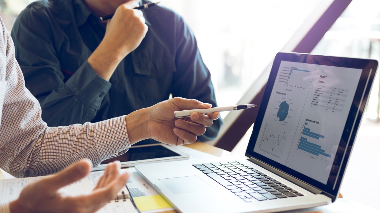 Two businessmen are together analyzing the financial data graph