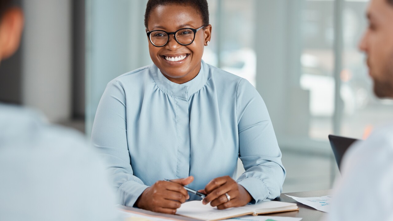 A Black woman smiling at her colleagues.