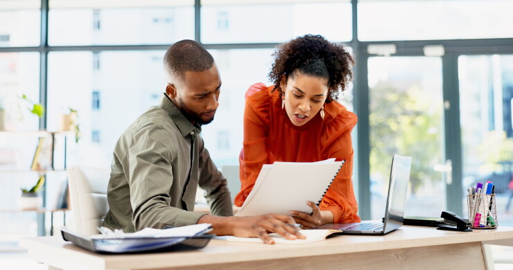 Two employees looking at paperwork, choosing, talking