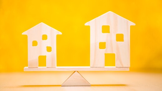Big and small home model with investment goal of the victory for ones success put on the scales on yellow background in the office, Real estate business investment concept.