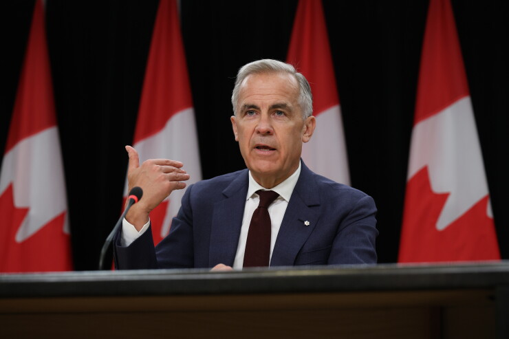 Mark Carney, Canada's prime minister speaking, with Canadian flags behind him