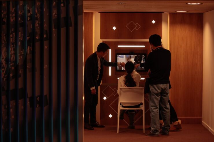 Three people use a screen installation demonstrating deepfake technology inside the Congress Center.