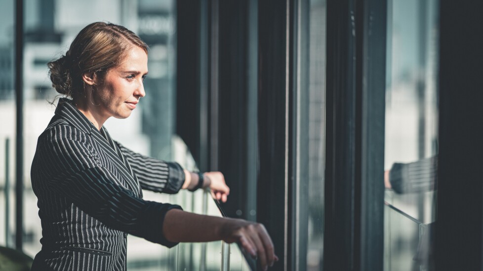 Woman in business clothes leaning against office window, corporate, executive