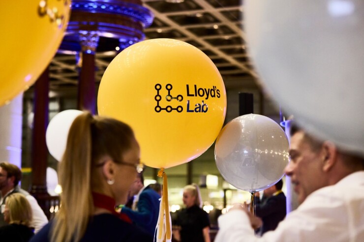 Yellow balloon with logo for Lloyd's Lab and party guests talking around it.
