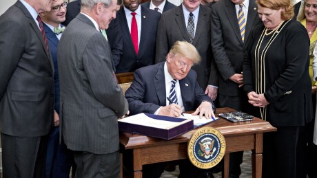 President Donald Trump signs S. 2155, the Economic Growth, Regulatory Relief, And Consumer Protection Act, with administration officials and members of Congress in the Roosevelt Room of the White House.