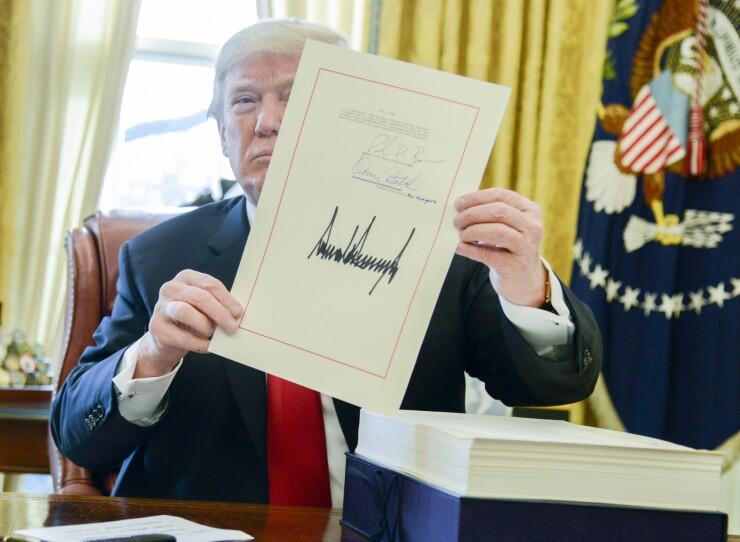 President Donald Trump holds up a tax-overhaul bill after signing it into law in the Oval Office.