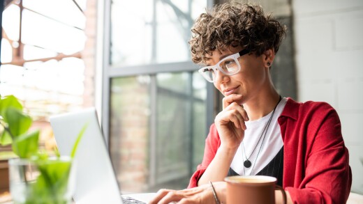 Busy young elegant woman in eyeglasses looking at laptop display
