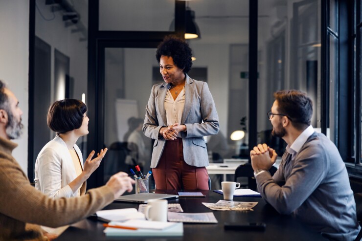 Female business leader standing in front of table of employees