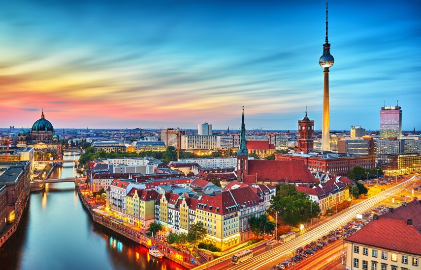 Berlin, Germany skyline, with historical buildings with red roof-tops towards the foreground and modern skyscrapers in the background; a river goes through the city