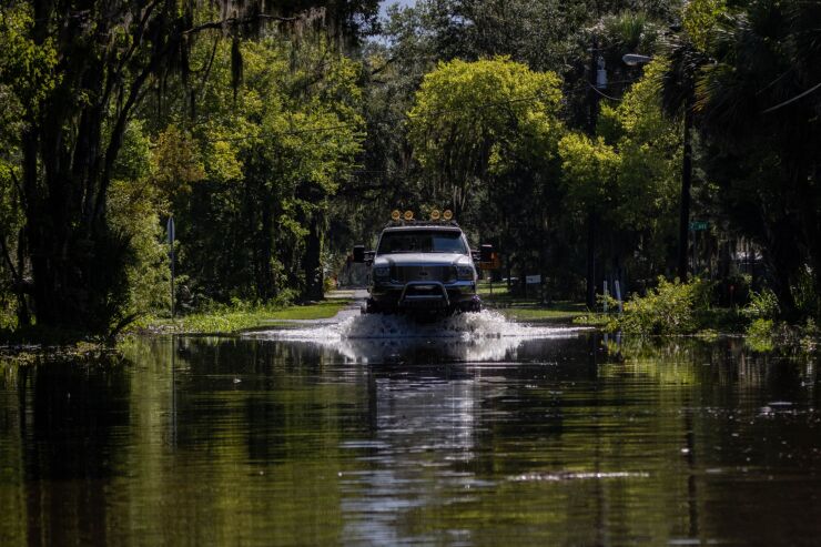 A lifted truck drives through flood waters after Hurricane Idalia