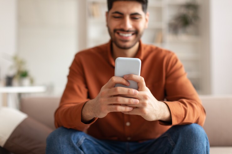 Man sitting on the couch and looking at his phone.