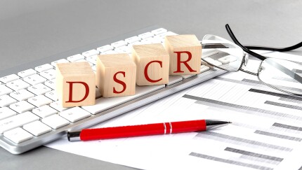 DSCR written on a wooden cube on the keyboard with chart on grey background