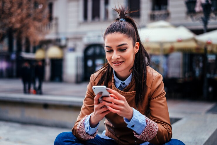 Woman sitting outside in jacket on cell phone
