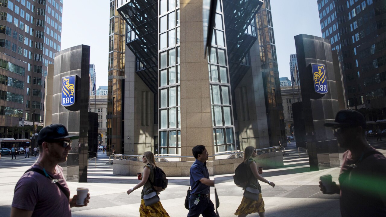 Pedestrians are reflected on a surface outside the Royal Bank of Canada head office in the financial district of Toronto.
