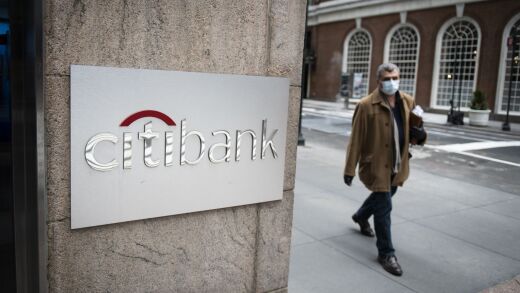 A pedestrian wearing a protective mask walks past a Citibank branch in New York on April 10, 2020.
