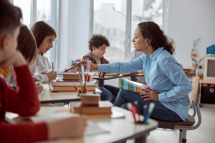 Teacher sitting with students, helping