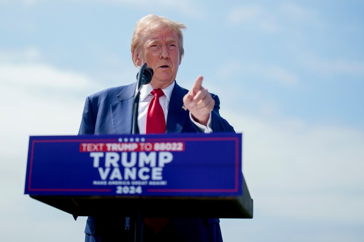 Former President Donald Trump pointing his finger behind a Trump - Vance campaign lectern