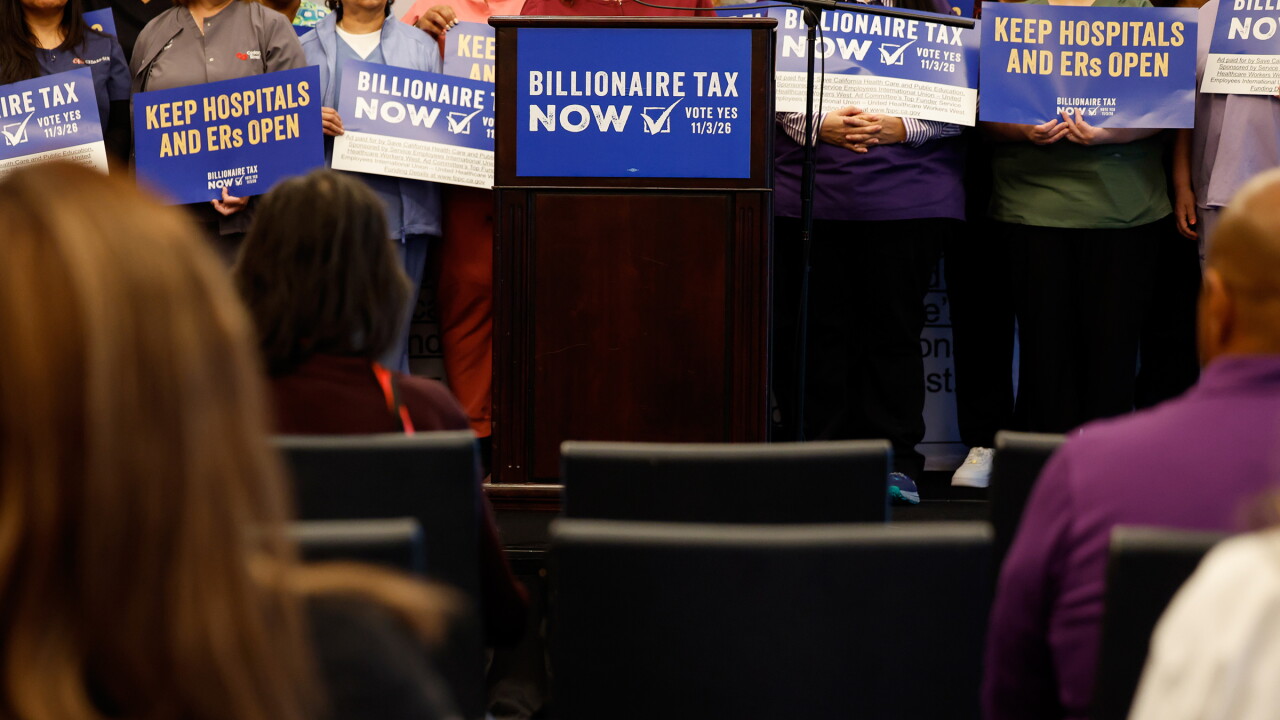 Supporters hold signs advocating for the Billionaire Tax Now coalition during a news conference in Los Angeles.